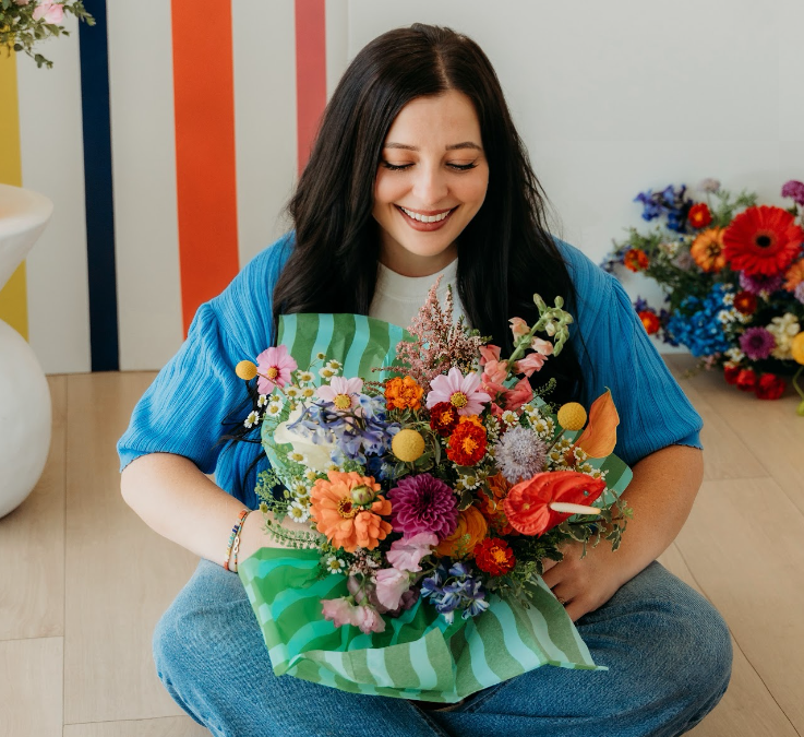 A woman holding a colorful bouquet in the Flourishing Minds studio