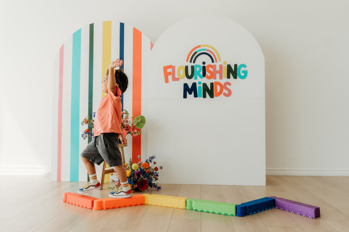 A child on colorful balance blocks in front of the Flourishing Minds logo