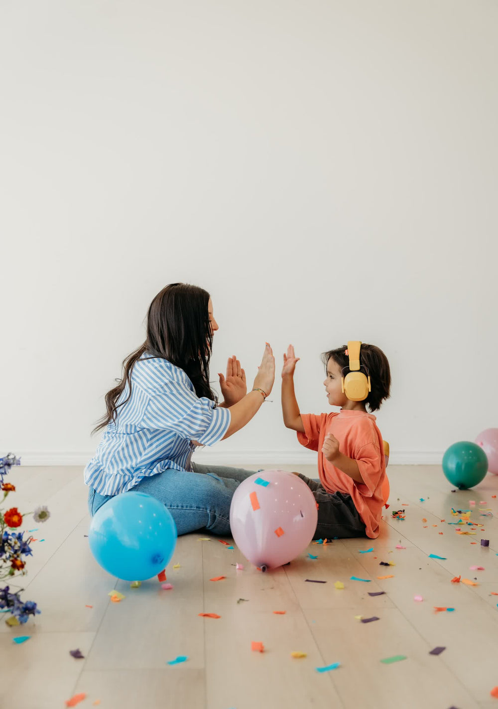 Mom and Elliot sharing a high five among colorful balloons
