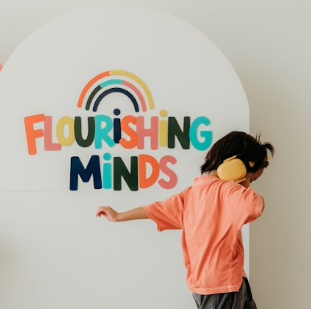 Child wearing headphones in front of the Flourishing Minds backdrop