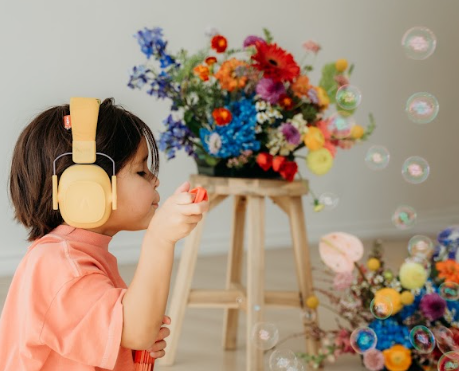 A child listening to music beside a colorful flower arrangement
