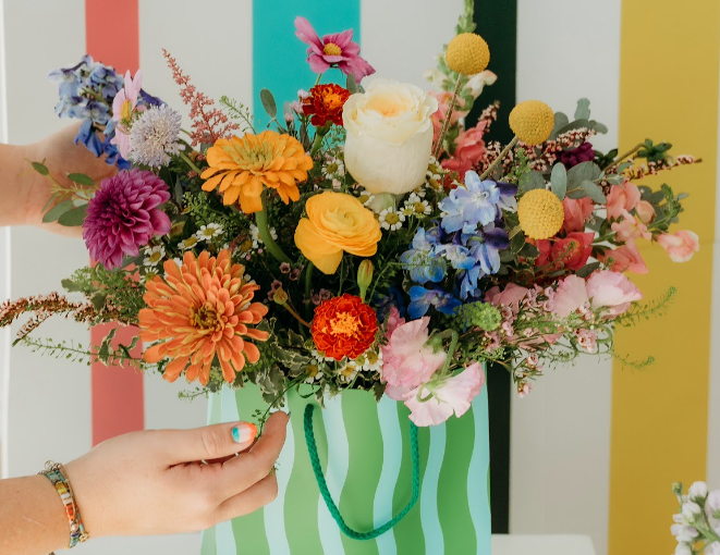 A child standing beside a colorful flower arrangement