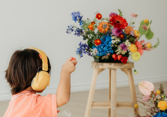 A child listening to music beside colorful flowers
